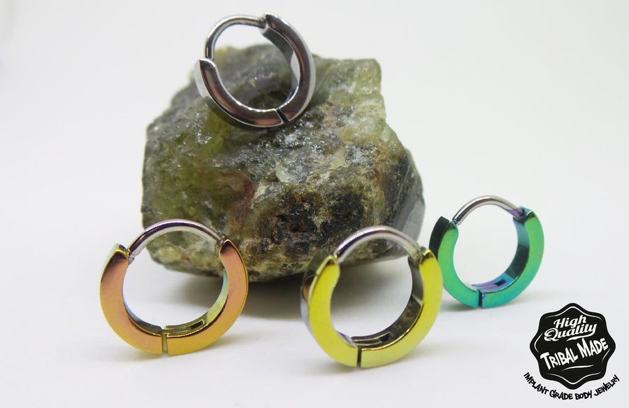 Titanium snap-lock clicker rings in silver, gold and green finishes on stone