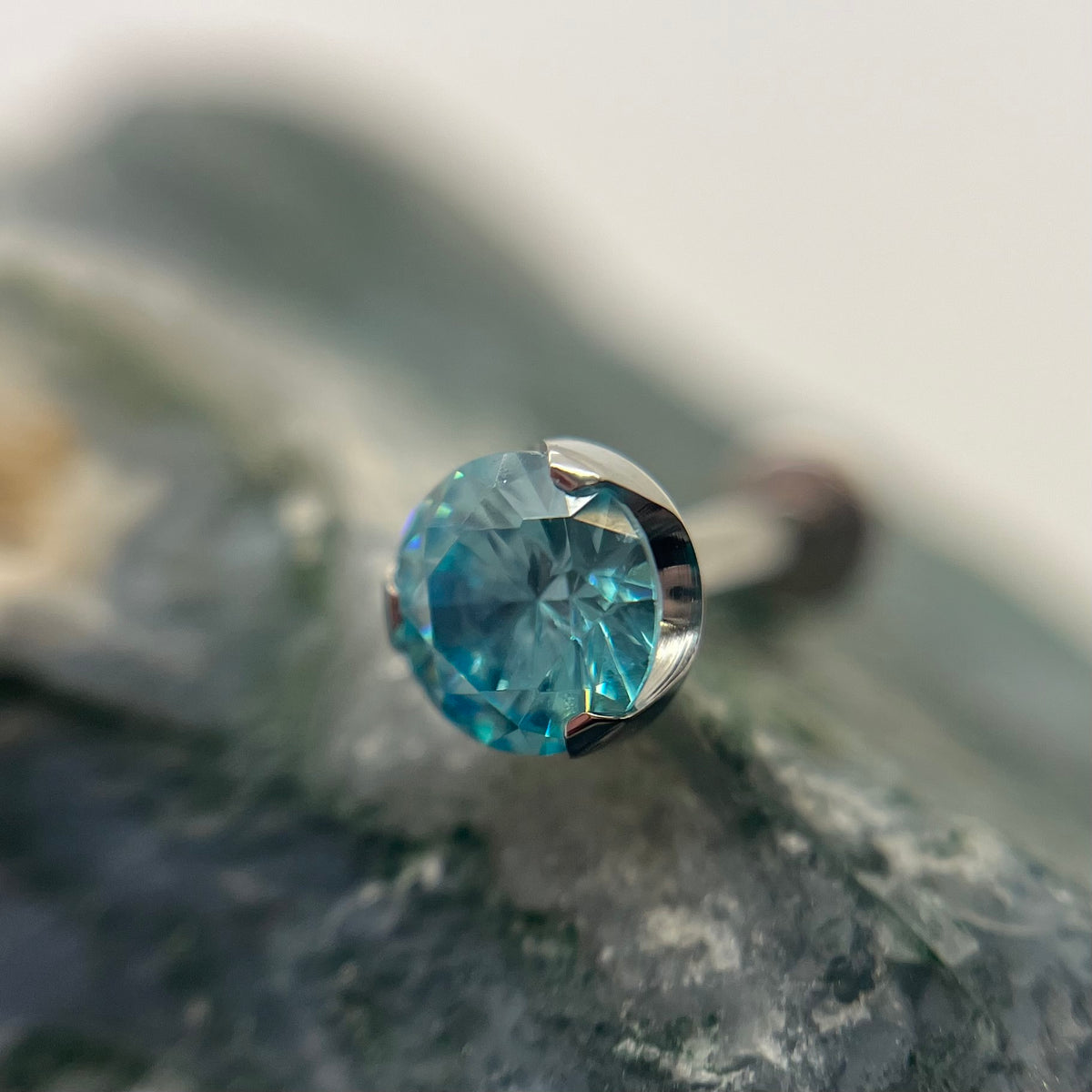 Aqua-coloured 3 mm prong-set titanium bead with backing, made in Calgary by Tribal Expression